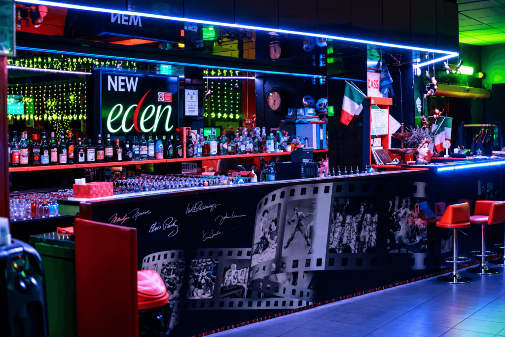 Bancone bar dell’Eden con insegna e bottiglie